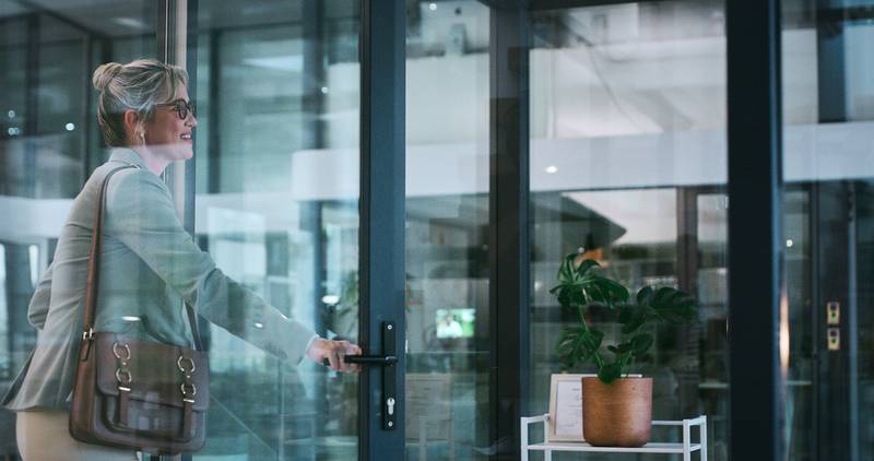 middle aged businesswoman smiling while exiting the building