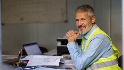 construction owner in green vest smiling